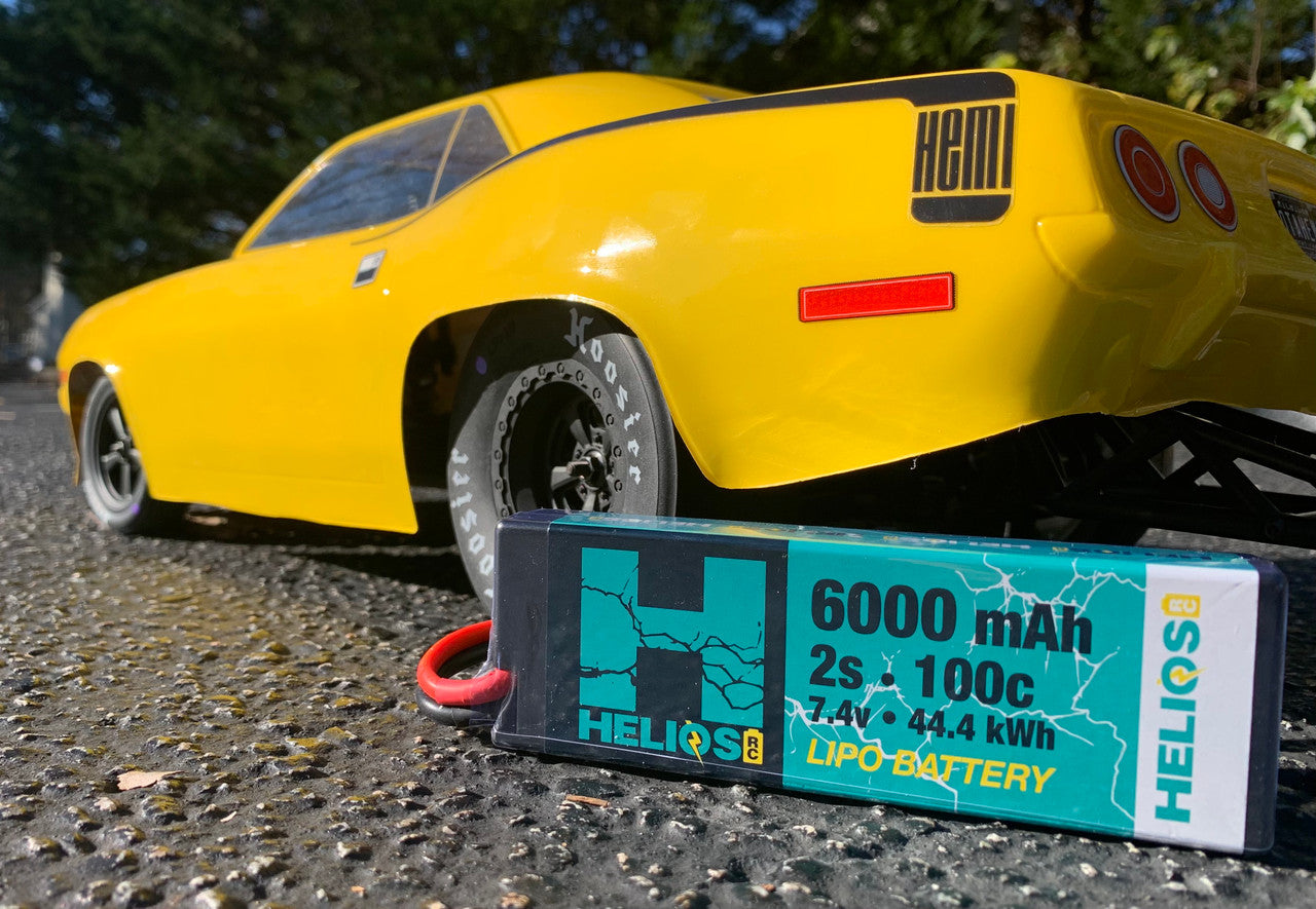 6000 mAh 2s 100c 7.4v 44.4kWh lipo battery infront of a yellow rc dodge challenger